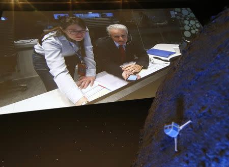 Paolo Ferri (R) Head of Rosetta Mission Operations, seen on a video projection behind a model of the Philae lander, reacts after the successful landing of the lander on comet 67P/ Churyumov-Gerasimenko, at the European Space Agency's (ESA) headquarters in Darmstadt November 12, 2014. REUTERS/Ralph Orlowski