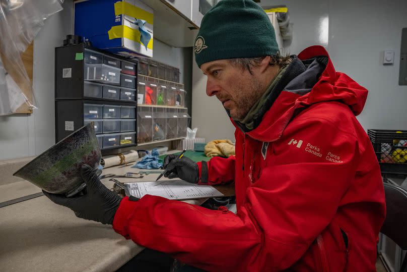 El arqueólogo subacuático Charles Dagneau examina un cuenco de cerámica excavado en el cofre de un marinero en el pecio del HMS Erebus, 17 de septiembre de 2023.