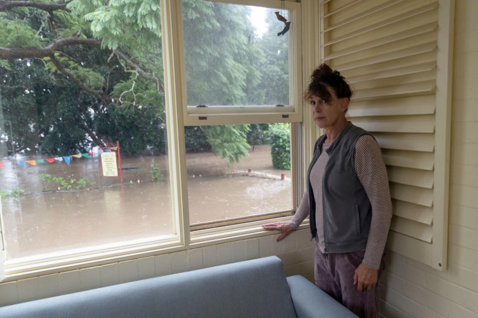 Windsor resident Kelly Miller shows concern as flood waters reach her workplace, a 100 year old property near the Windsor CBD in Sydney.