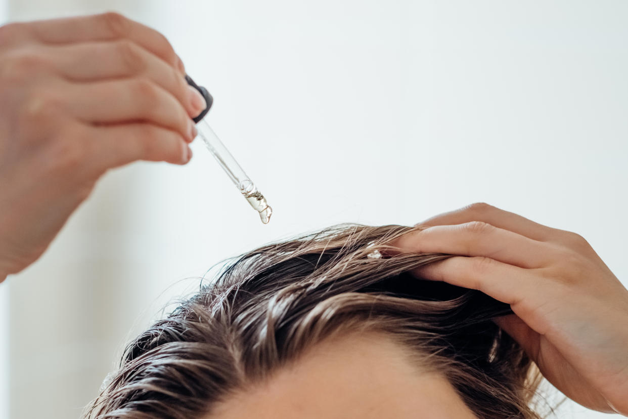 Woman applies oil to her hair with pipette