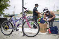 In this Thursday, May 28, 2020, photo, Tina Grace packs groceries into a bag for easier transportation on her bicycle during a food distribution drive sponsored by Island Harvest Food Bank in Valley Stream, N.Y. (AP Photo/Mary Altaffer)