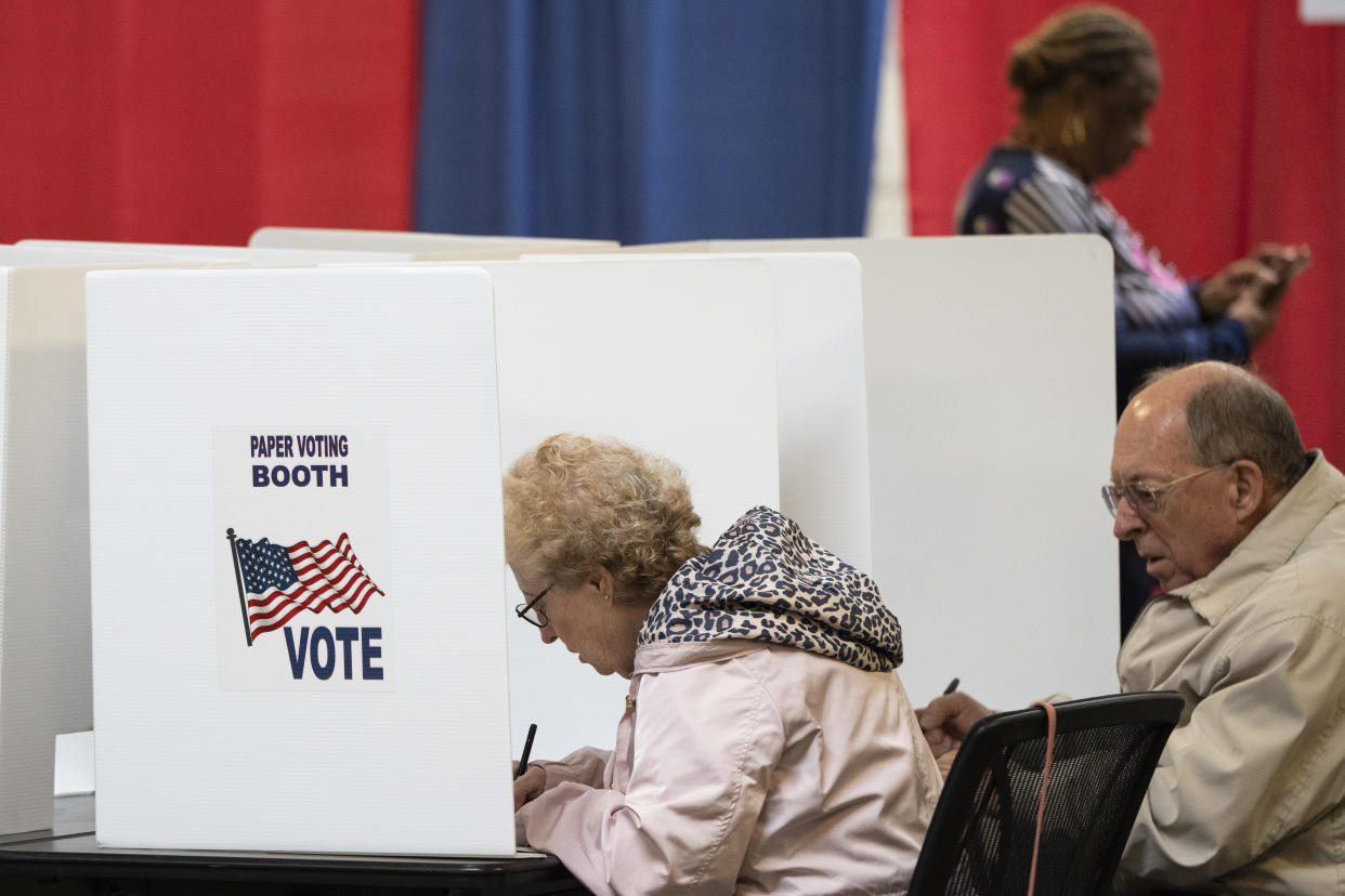 Voters fill out paper ballots at voting booths. 