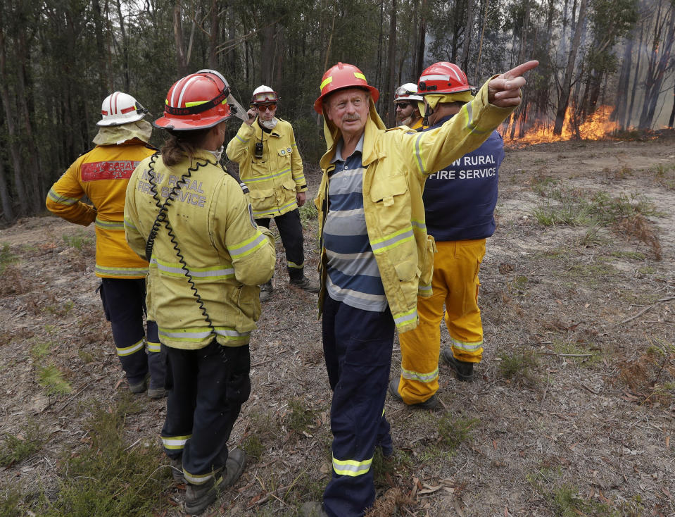 Doug Schutz, 3rd right, the Tomerong Rural Fire Service Captain, oversees a controlled burn near Tomerong, Australia, Wednesday, Jan. 8, 2020, set in an effort to contain a larger fire nearby. Schutz began volunteering with the Rural Fire Service in New South Wales some 53 years ago, at the age of 13. That was back in the days when the fire truck was a Land Rover that towed a trailer with a water pump on top. Schutz is part of an army of 72,000 people from across the state who make up the world's largest volunteer fire service. (AP Photo/Rick Rycroft)