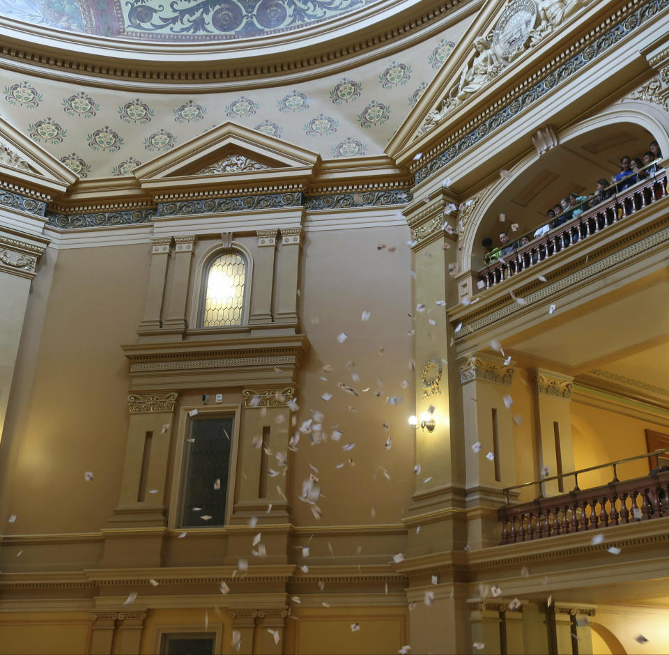 Several thousand leaflets drop from the fifth-floor rotunda at the Kansas Statehouse in a protest for Medicaid expansion, Friday, May 3, 2019, in Topeka, Kansas. About 15 protesters participated in dropping the leaflets, which depicted overdue hospital bills spattered with blood. Kansas legislators who support expanding Medicaid plan to try and block passage of the next state budget in hopes of forcing a vote on an expansion plan.(AP Photo/John Hanna)