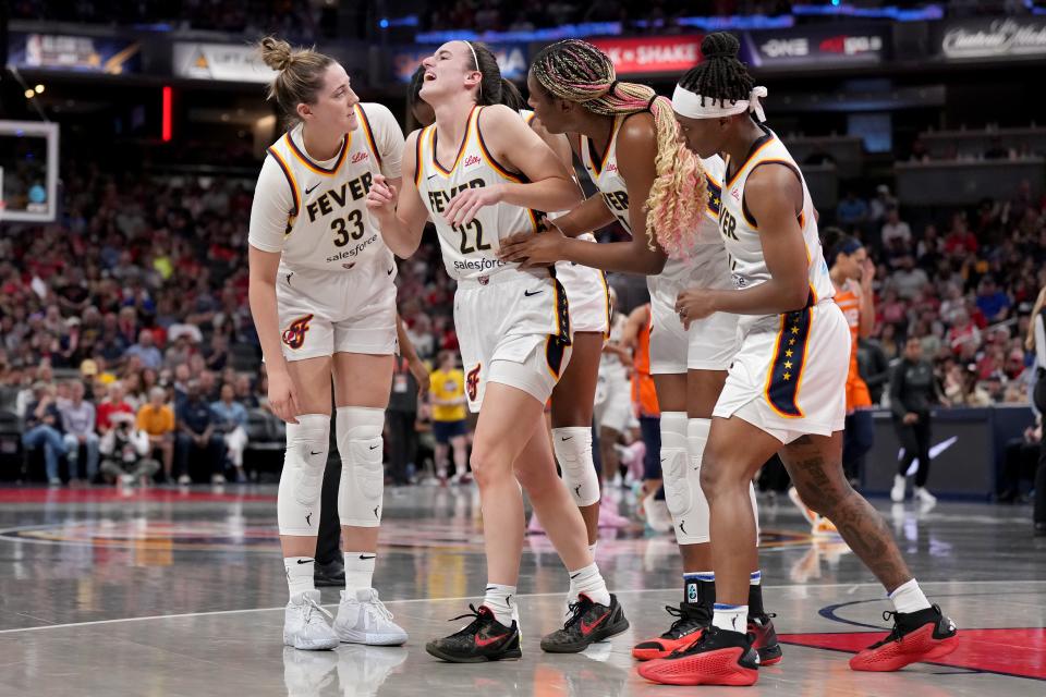 Indiana Fever teammates help Caitlin Clark (22) off the court after an apparent injury.