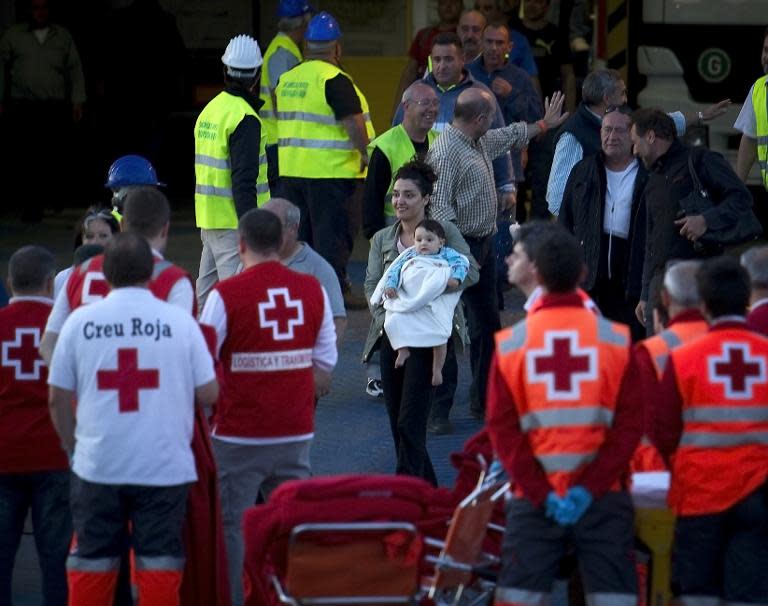 A woman and infant disembark from a ship in the port of Palma de Mallorca after the passenger ferry they were travelling on caught fire off Spain's Balearic Islands in the Mediterranean