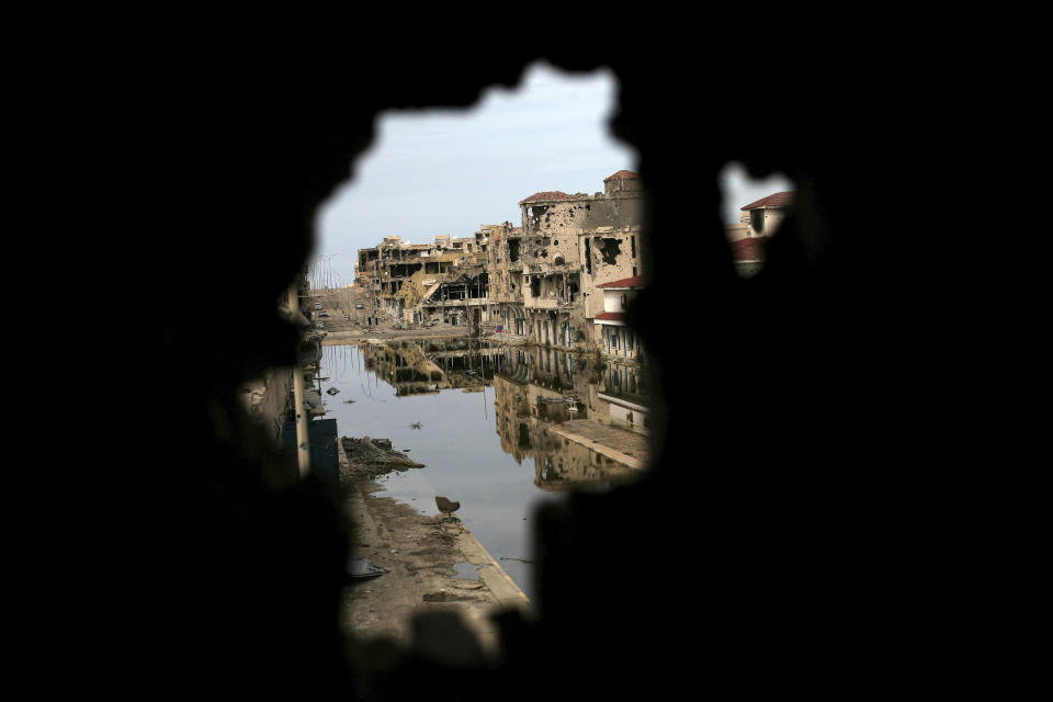 File - In this Saturday, Oct. 22, 2011 file photo, buildings ravaged by fighting are seen through another damaged building in Sirte, Libya. Ten years ago, an uprising in Tunisia opened the way for a wave of popular revolts against authoritarian rulers across the Middle East known as the Arab Spring. For a brief window as leaders fell, it seemed the move toward greater democracy was irreversible. Instead, the region saw its most destructive decade of the modern era. Syria, Yemen, Libya and Iraq have been torn apart by wars, displacement and humanitarian crisis. (AP Photo/Manu Brabo)