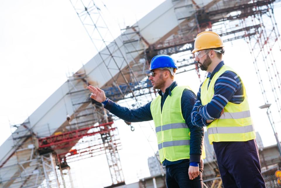 Two people wearing hard hats and personal protective equipment in an industrial setting.