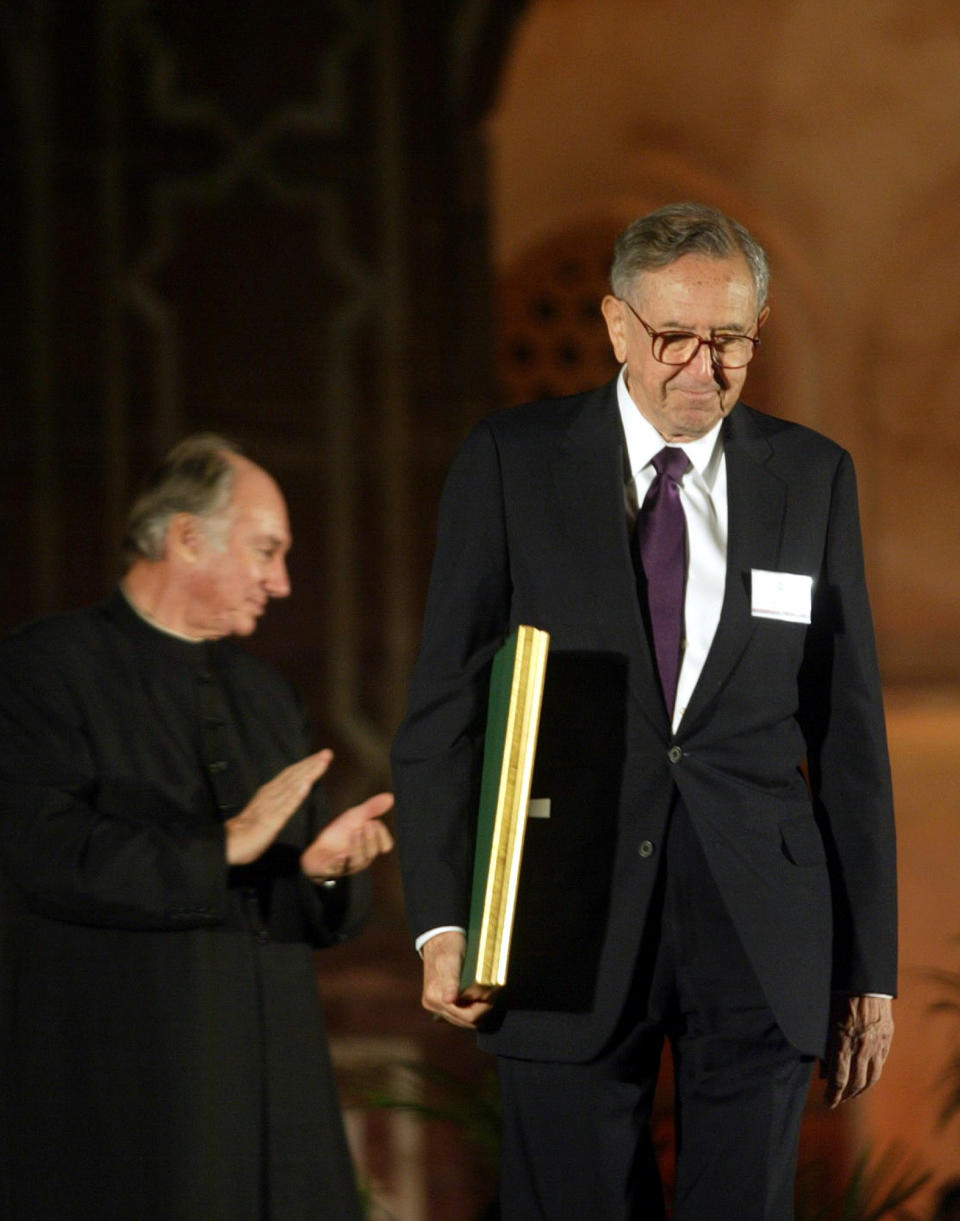 FILE - In this Nov. 27, 2004 file photo, Cesar Pelli of Cesar Pelli and Associates US, right, one of the awardees of the Aga Khan Award for Architecture walks with his award as the Aga Khan, spiritual leader of the Shia Imami Ismaili Muslims, claps during the award ceremony at the gardens of Emperor Humayuns Tomb in New Delhi, India. Pelli, known for designing some of the world’s tallest and most iconic buildings, has died. He was 92. Anibal Bellomio, a senior associate architect at Pelli’s Connecticut studio, confirmed Saturday, July 20, 2019, that Pelli died peacefully on Friday at his home in New Haven. (AP Photo/Manish Swarup)