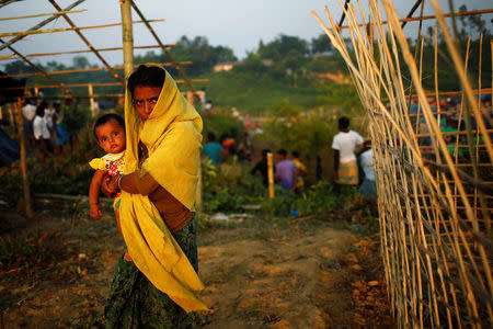 A Rohingya refugee woman with her child reacts to the camera while walking in a newly build makeshift camp, in Cox's Bazar, Bangladesh September 16, 2017. REUTERS/Mohammad Ponir Hossain