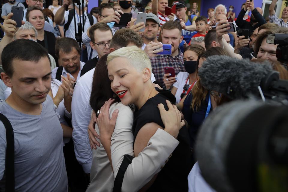 FILE - In this Aug. 9, 2020, file photo, Sviatlana Tsikhanouskaya, candidate for the presidential elections, center left, and Maria Kolesnikova, a representative of Viktor Babariko, center right, greet each other at a polling station during the presidential election in Minsk, Belarus. Kolesnikova, a professional flute player with no political experience, emerged as a key opposition activist in Belarus. She has appeared at protests of authoritarian President Alexander Lukashenko after he was kept in power by an Aug. 9 election that his critics say was rigged. (AP Photo/Sergei Grits, File)