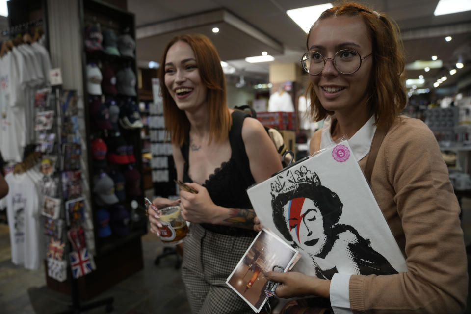 Customers purchase a T-shirt with a print of Queen Elizabeth II at a gift shop in London, Monday, Sept. 12, 2022. Just days after the death of Queen Elizabeth II, unofficial souvenirs have rolled out at royal-themed gift shops in London and online marketplaces like Amazon and Etsy. (AP Photo/Kin Cheung)