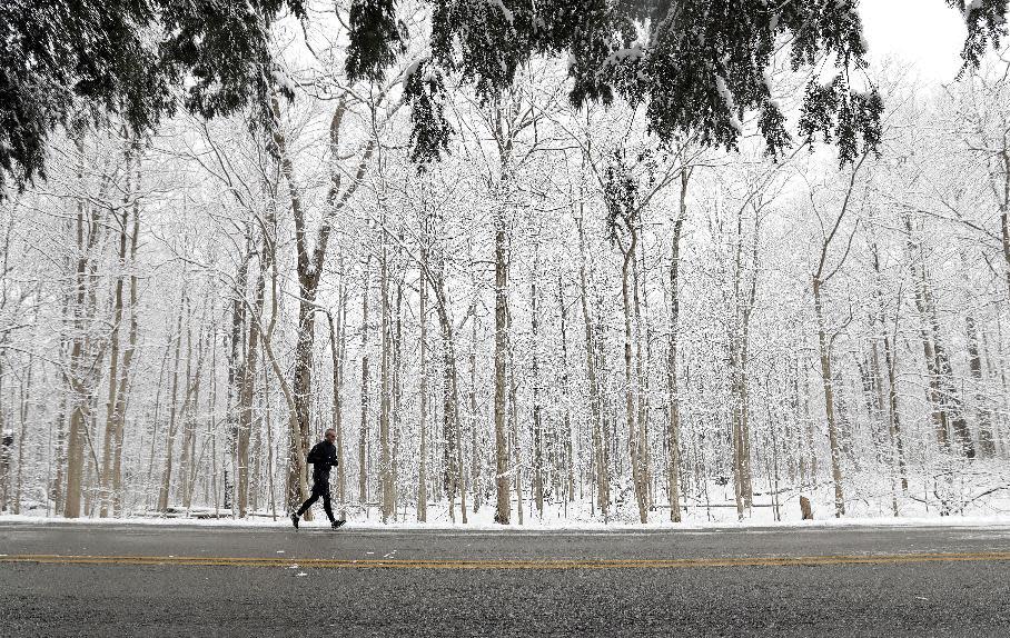 A runner goes for a run in Eagle Creek Park as snow falls Tuesday, Dec. 13, 2016, in Indianapolis. (AP Photo/Darron Cummings)