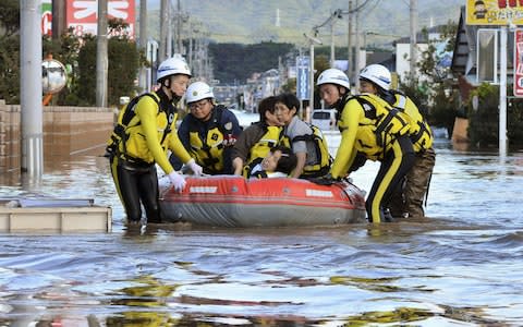 Local residents sit in a boat as they are rescued from a flooded residential area following Typhoon Hagibis in Iwaki, Fukushima - Credit: JAPAN OUT/Reuters