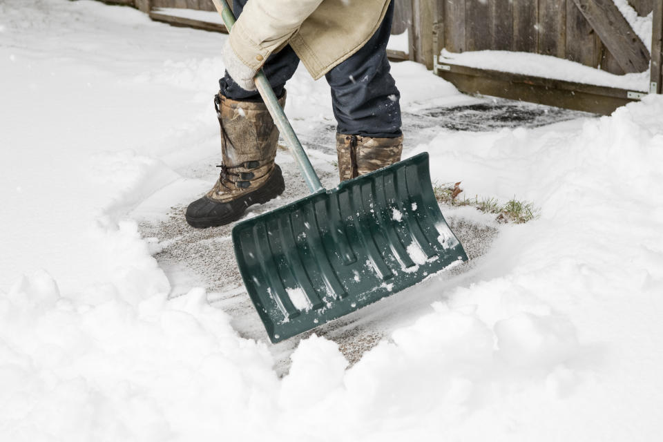 Man using a snow shovel to clear snow from sidewalk