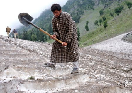 A Kashmiri Muslim man cuts snow to make way for Hindu pilgrims to trek to reach the holy Amarnath cave shrine, near Pahalgam