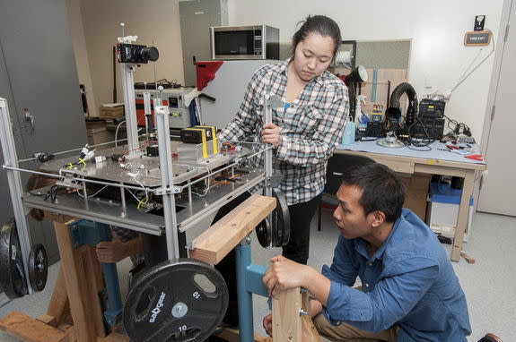 At the Hawaii Space Flight Laboratory, avionics engineer Amber Imai and satellite avionics assistant Tristan Martinez adjust the satellite’s attitude determination and control test bed.