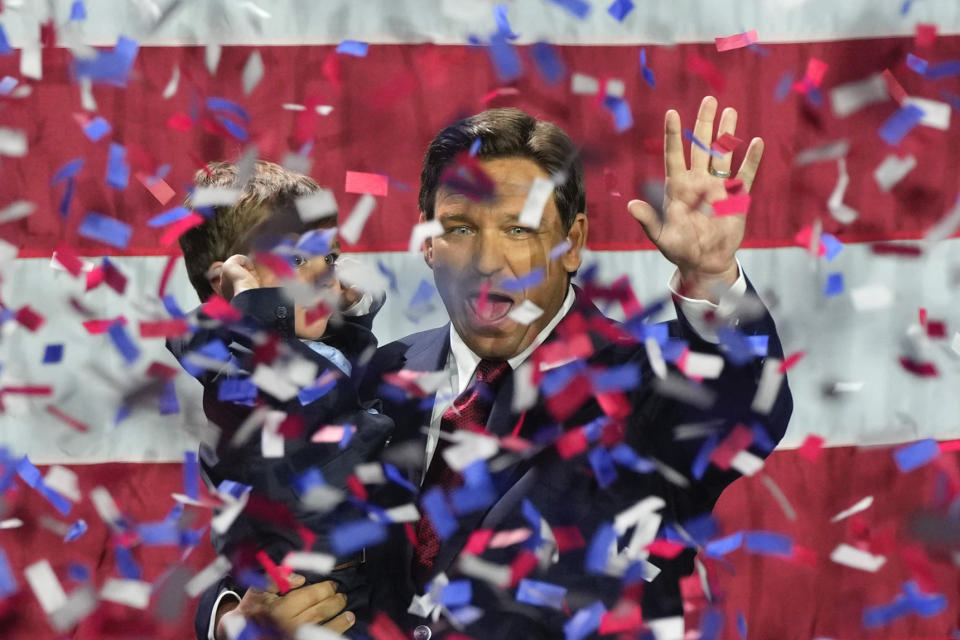 Gov. Ron DeSantis cheers, with his toddler son Mason, hands to his ears, not quite as enthusiastic, in a blizzard of red, white and blue confetti. 