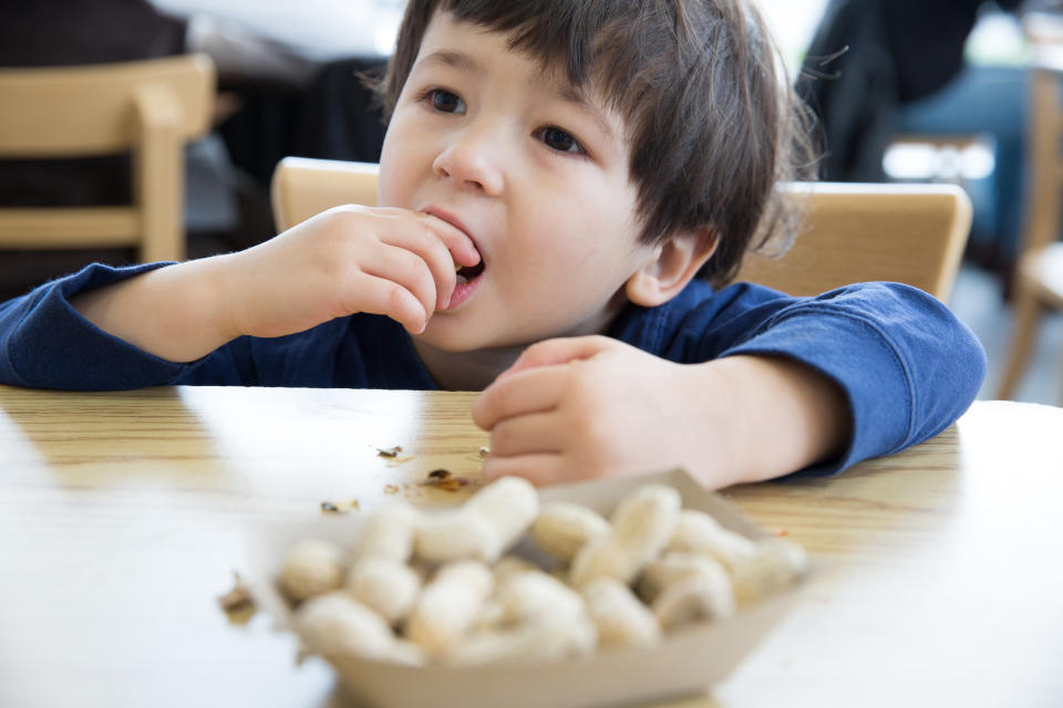 Little boy eating peanuts at a table in a restaurant