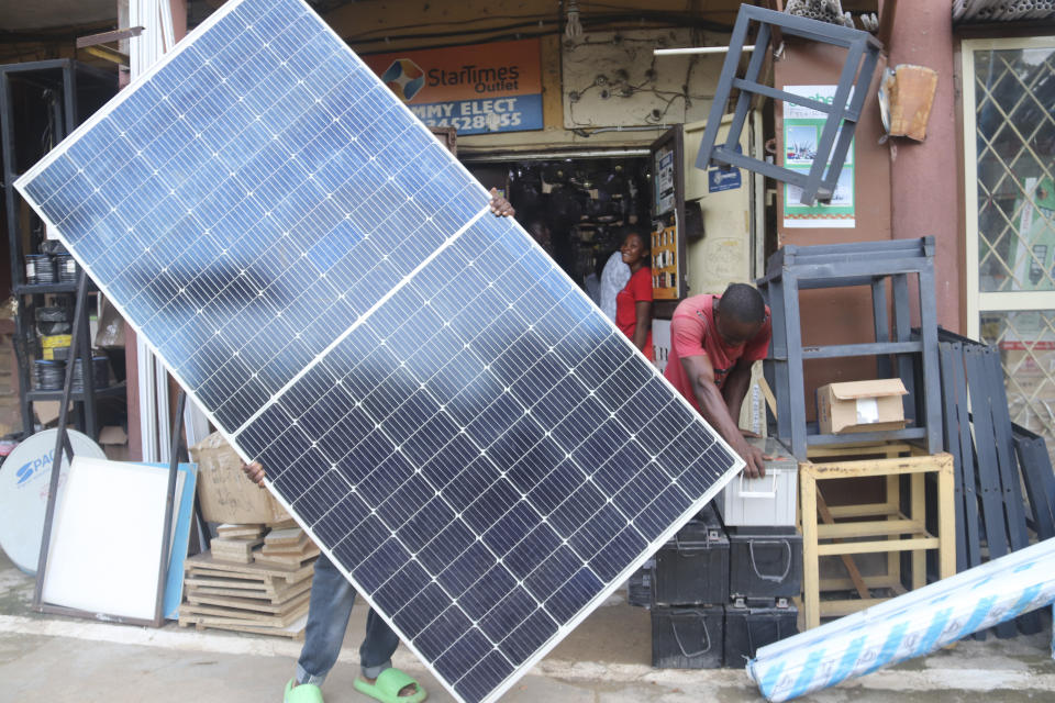 A man displays a solar panel for sale at a shop Abuja, Nigeria. Saturday June 17, 2023. Nigeria's removal of a subsidy that helped reduce the price of gasoline has increased costs for people already struggling with high inflation. But it also potentially accelerates progress toward reducing emissions in Africa's largest economy. (AP Photo/Olamikan Gbemiga)