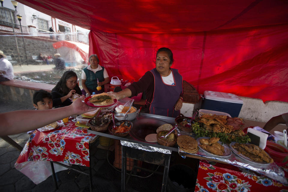 A woman serves tacos at a street restaurant at San Andres Mixquic, just outside Mexico City, Monday, March 30, 2020, amid the worldwide spread of the new coronavirus. (AP Photo/Fernando Llano)