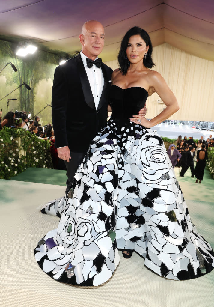 Jeff Bezos and Lauren Sanchez on red carpet; Sanchez in a black-and-white floral gown with Bezos in a tuxedo