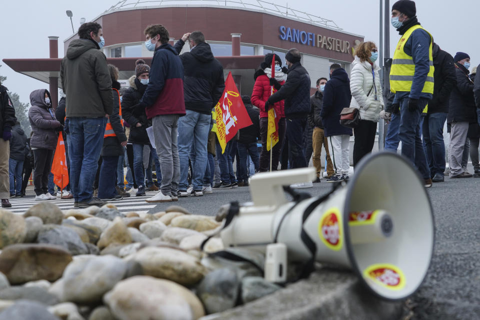 Striking workers gather outside the French pharmaceutical company Sanofi headquarters in Marcy l'Etoile, central France, Tuesday, Jan.19, 2021. Employees of pharmaceutical company Sanofi stage a protest against planned redundancies that they say could slow the fight against the Coronavirus pandemic . Sanofi had been developing Covid vaccines but will not be ready to roll out until late 2021. (AP Photo/Laurent Cipriani)