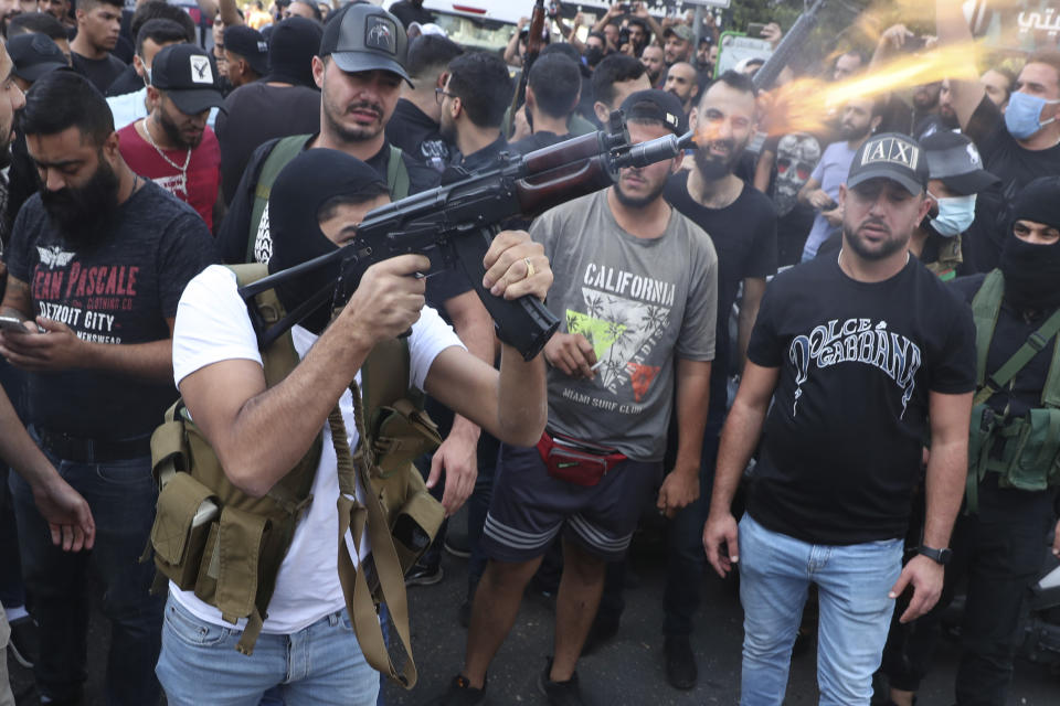 Supporters of the Shiite Amal group fire weapons in the air during the funeral processions of Hassan Jamil Nehmeh, who was killed during yesterday clashes, in the southern Beirut suburb of Dahiyeh, Lebanon, Friday, Oct. 15, 2021. Dozens of gunmen opened fire in the air Friday south of Beirut during the funeral of persons killed in hours of gun battles between heavily armed gunmen the day before that left several people dead and terrorized the residents of Beirut. (AP Photo/Bilal Hussein)