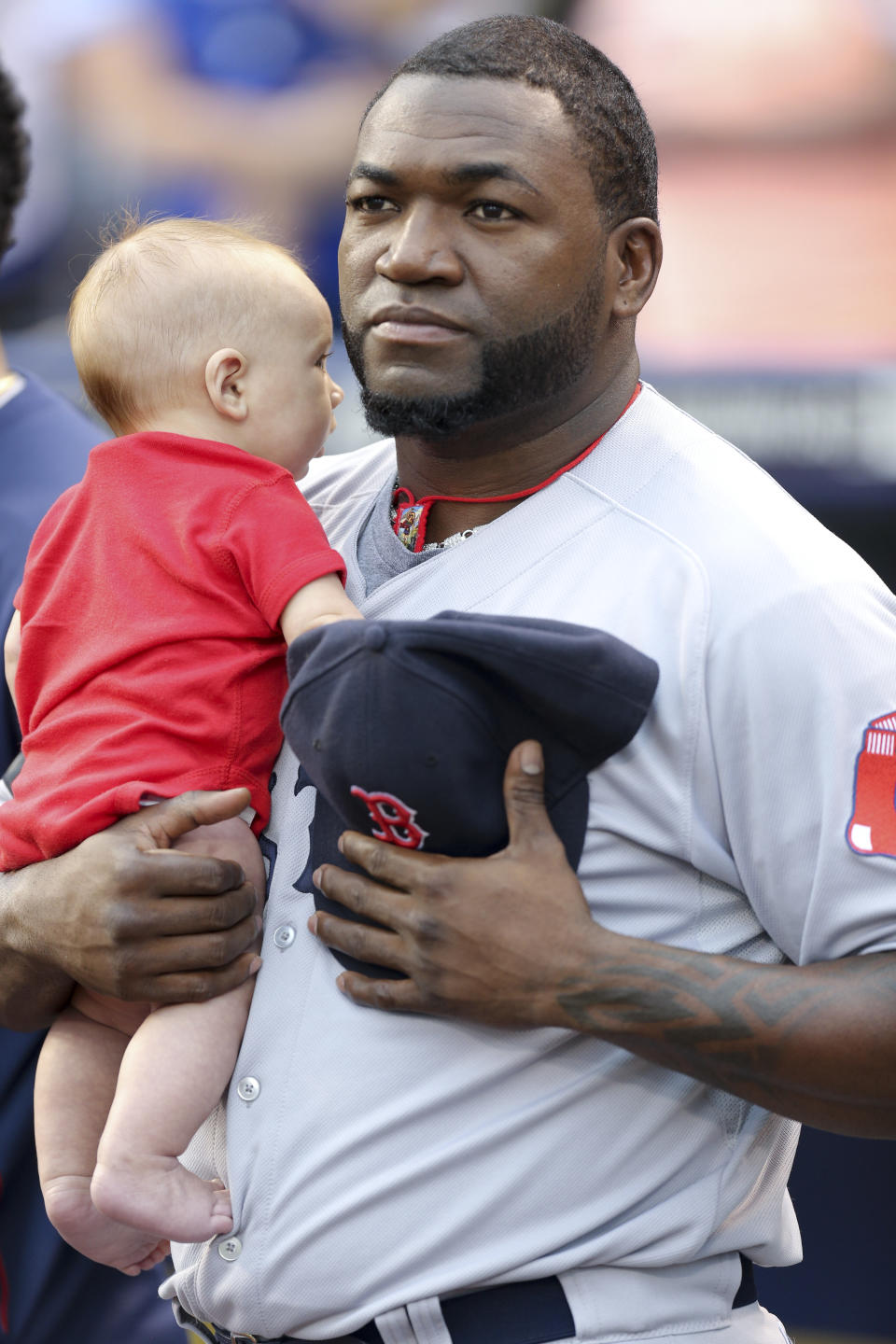 KANSAS CITY, MO - AUGUST 8:  David Ortiz #34 of the Boston Red Sox holds a fan's child during the singing of the 'National Anthem' prior to a game against the Kansas City Royals at Kauffman Stadium August, 8, 2013 in Kansas City, Missouri.  (Photo by Ed Zurga/Getty Images)