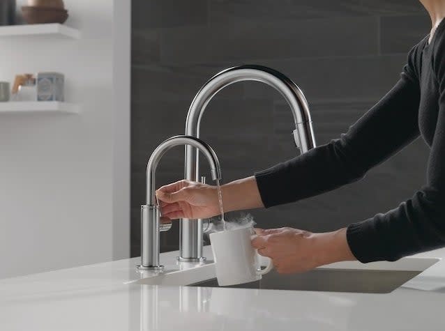 a person using the hot water tap to fill a mug