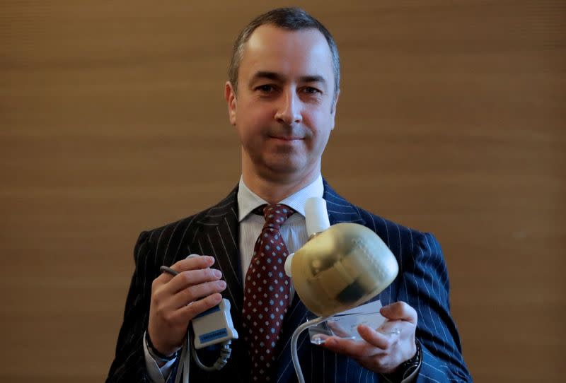 Carmat Chief Executive Officer Stephane Piat holds an artificial heart as he poses after the company's news conference in Paris