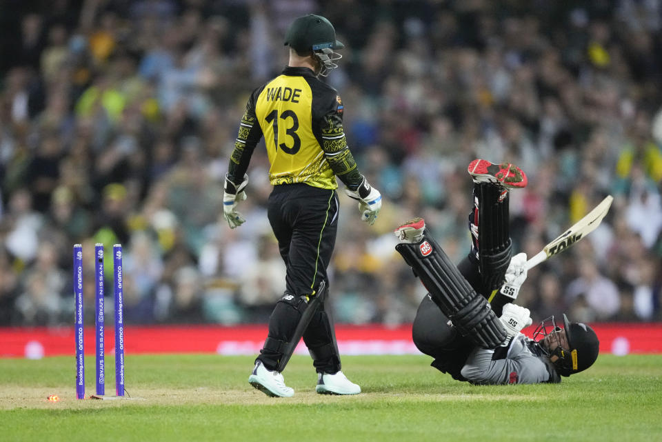 New Zealand's Devon Conway falls as Australia's Matthew Wade watches during the T20 World Cup cricket match between Australia and New Zealand in Sydney, Australia, Saturday, Oct. 22, 2022. (AP Photo/Rick Rycroft)