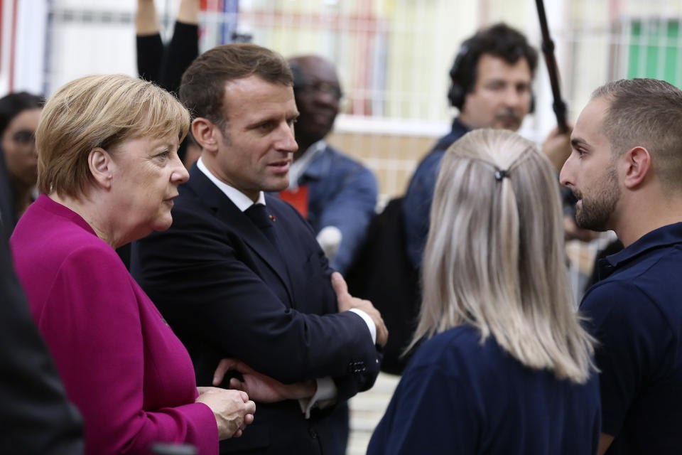 French President Emmanuel Macron, second left, and German Chancellor Angela Merkel talk to Airbus French and German employees after visiting the assembly line of the Airbus A350 in Toulouse, southwestern France, Wednesday, Oct.16, 2019. French President Emmanuel Macron and German Chancellor Angela Merkel are meeting in southern France, one day before a key EU summit that may approve a divorce deal with Britain. (AP Photo/Frederic Scheiber, Pool)