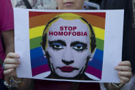 FILE - A woman holds a poster depicting Russian President Vladimir Putin during a protest in front of the Russian embassy in Madrid, Spain, Friday Aug. 23, 2013 against Russia's new law on gays. Russia passed a law in 2013 that bans the depiction of homosexuality to minors, something human rights groups views as a way to demonize LGBT people and discriminate against them. (AP Photo/Paul White, File)