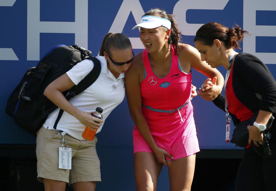 Peng Shuai of China is tended to as she begins to cramp up during the semi-final match against Caroline Wozniacki of Denmark at the 2014 U.S. Open tennis tournament in New York, September 5, 2014. REUTERS/Adam Hunger