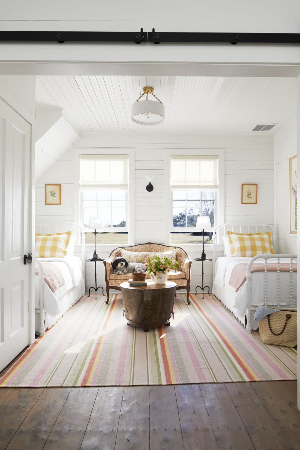 white bedroom with two twin beds and colorful striped rug