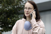 German tourist Katharina Genz speaks on a phone as she lines up outside the Christchurch Airport terminal as she waits to check in for a charter flight back to Germany via Vancouver from Christchurch, New Zealand, Monday, April 6, 2020. About 100,000 tourists found themselves stranded in New Zealand after it went into a strict lockdown 12 days ago in an attempt to limit the spread of the coronavirus. Genz said she is eager to get home to help out her family, although is dreading a planned period of self-isolation in father's empty apartment in Berlin before she can see them. (AP Photo/Mark Baker)