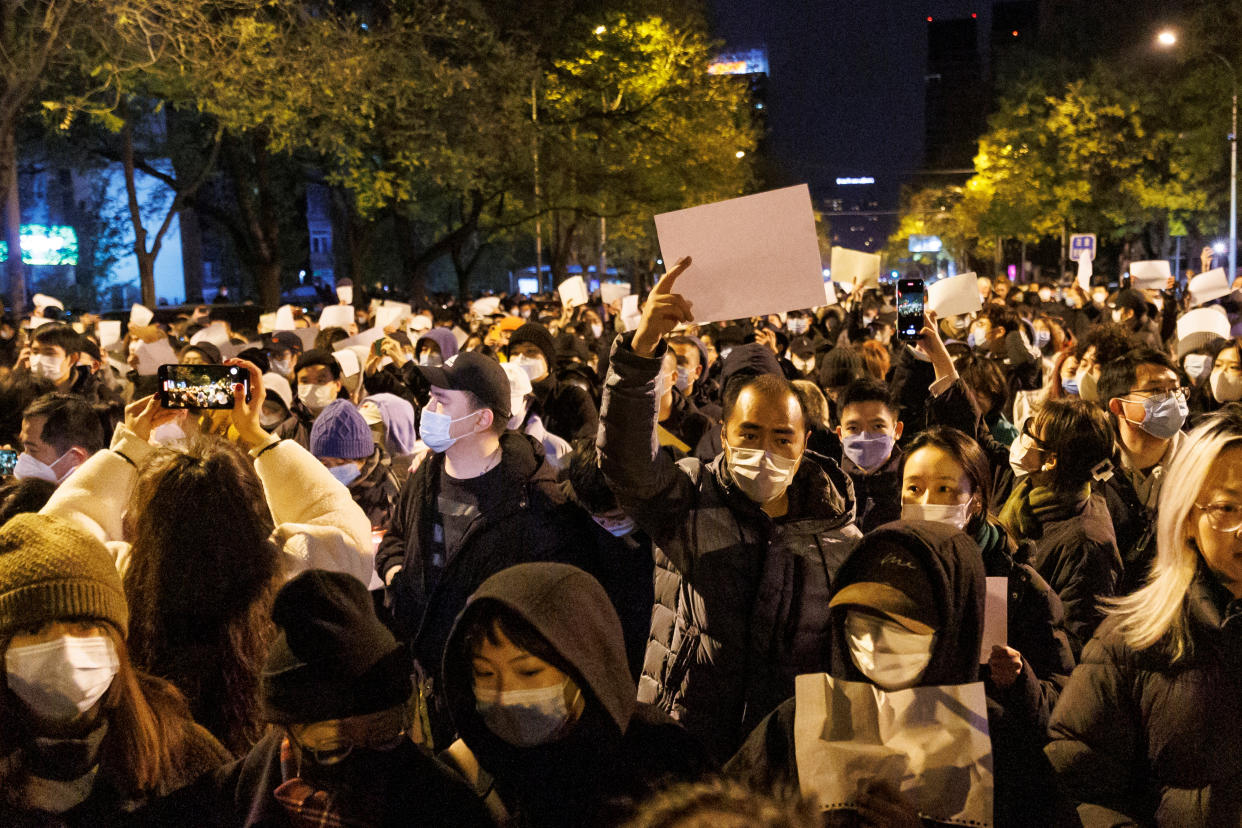 People hold white sheets of paper in protest of coronavirus disease (COVID-19) restrictions, after a vigil for the victims of a fire in Urumqi, as outbreaks of the coronavirus disease continue in Beijing, China, November 27, 2022. REUTERS/Thomas Peter