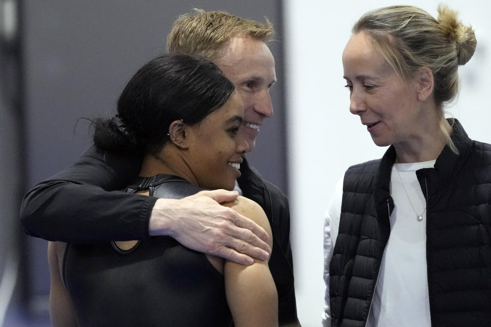 Gabby Douglas, left, gets a hug from coach Valeri Liukin as Anna Kotchneva smiles after competition at the American Classic Saturday, April 27, 2024, in Katy, Texas. (AP Photo/David J. Phillip)