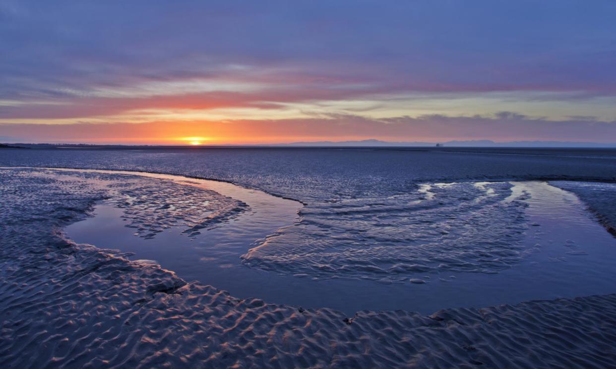 <span>The sun rising over mudflats at Sandyhills Bay on the Solway Firth, Dumfries and Galloway, Scotland.</span><span>Photograph: Mark Hamblin/The Wildlife Trusts</span>