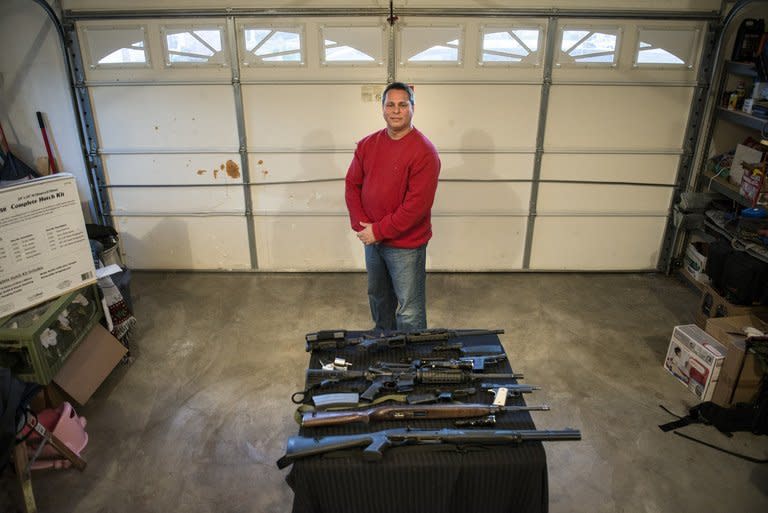 Patrick Troy, who is a force security instructor with the Blevins's preparedness group, poses with firearms including a M1 carbine rifle and an AR-15 rifle December 5, 2012 in Berryville, Virginia. A "prepper" describes a growing number of Americans making big plans for bad times, be it economic chaos, climate change, terrorism or natural disaster