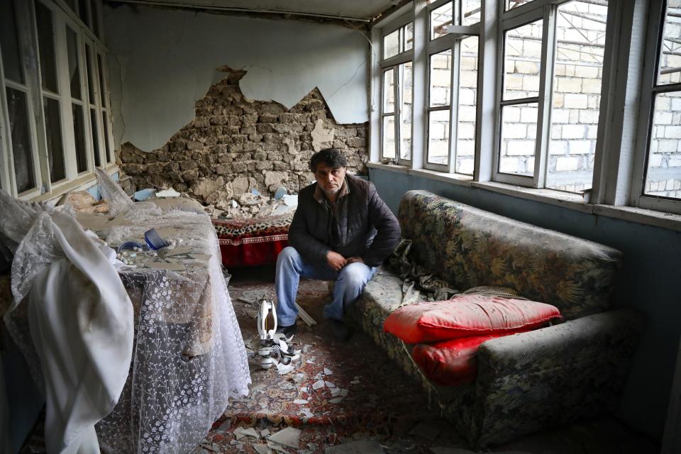 A man sits in his destroyed house in a residential area that was hit by rocket fire overnight by Armenian forces, early Saturday, Oct. 17, 2020, in Gyanga, Azerbaijan's second largest city, near the border with Armenia. (AP Photo/Aziz Karimov)