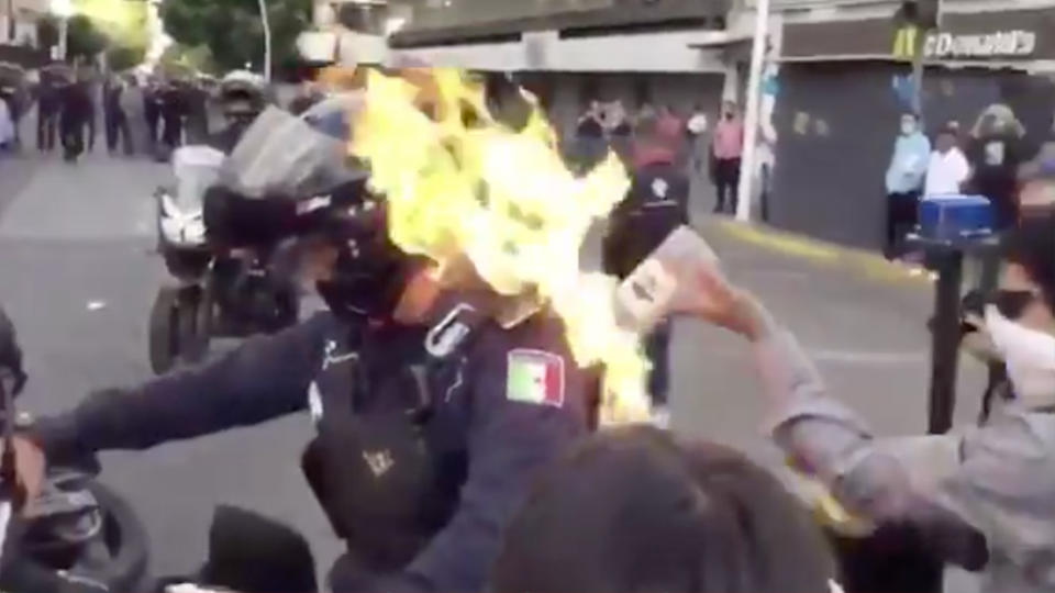 A police officer has been set on fire by a protester over the death of a man in custody.