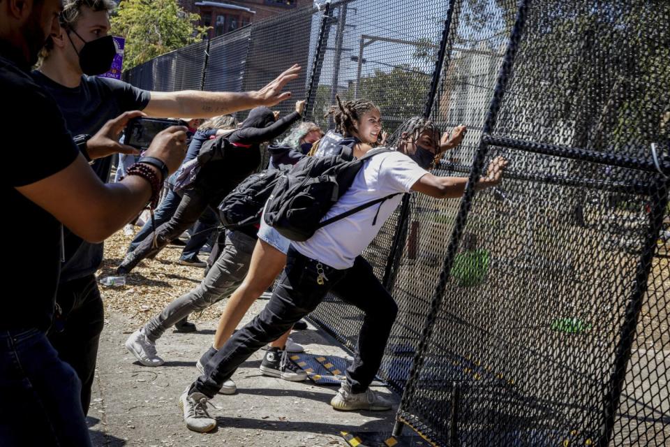 Several protesters attempt to push down a gate surrounding People's Park.