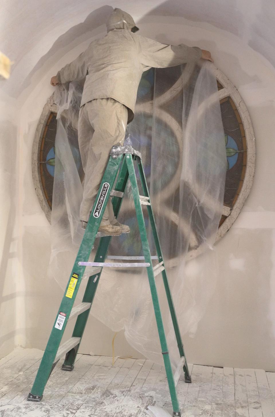 Chris Rojas covers a stained glass window while working to restore the West Baden First Baptist Colored Church in 2018.