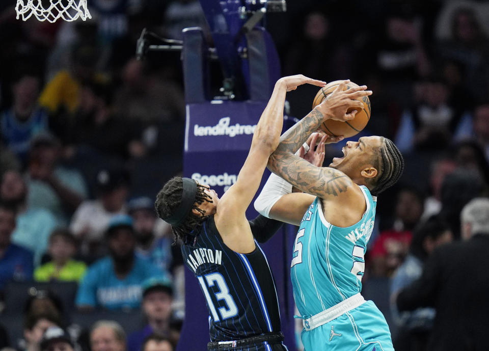 Orlando Magic guard R.J. Hampton, left, goes up against the shot of Charlotte Hornets forward P.J. Washington, right, during the first half of an NBA basketball game on Thursday, April 7, 2022, in Charlotte, N.C. (AP Photo/Rusty Jones)