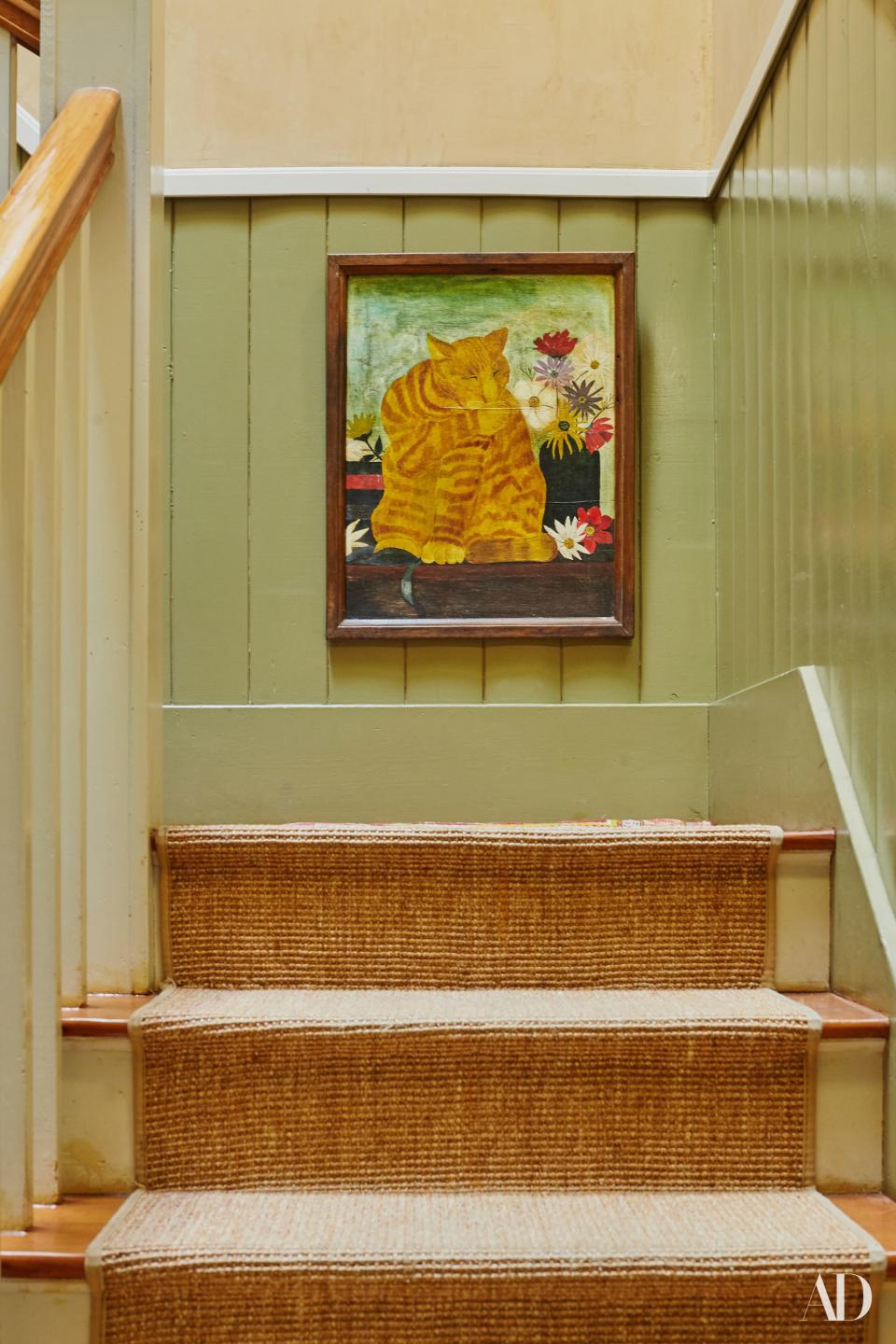 A painting of a cat and flowers—in keeping with the color scheme favored by Swedish painter Carl Larsson—is positioned on the staircase.