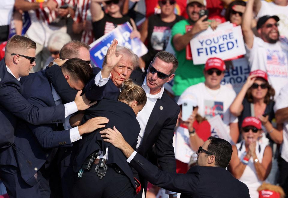 FILE PHOTO: Republican presidential candidate and former U.S. President Donald Trump gestures with a bloodied face while he is assisted by U.S. Secret Service personnel after he was shot in the right ear during a campaign rally at the Butler Farm Show in Butler, Pennsylvania, U.S., July 13, 2024. REUTERS/Brendan McDermid//File Photo