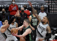 Boston Celtics guard Payton Pritchard, center, drives to the basket on Portland Trail Blazers center Enes Kanter, right, and guard Damian Lillard, right, during the first half of an NBA basketball game in Portland, Ore., Tuesday, April 13, 2021. (AP Photo/Steve Dykes)