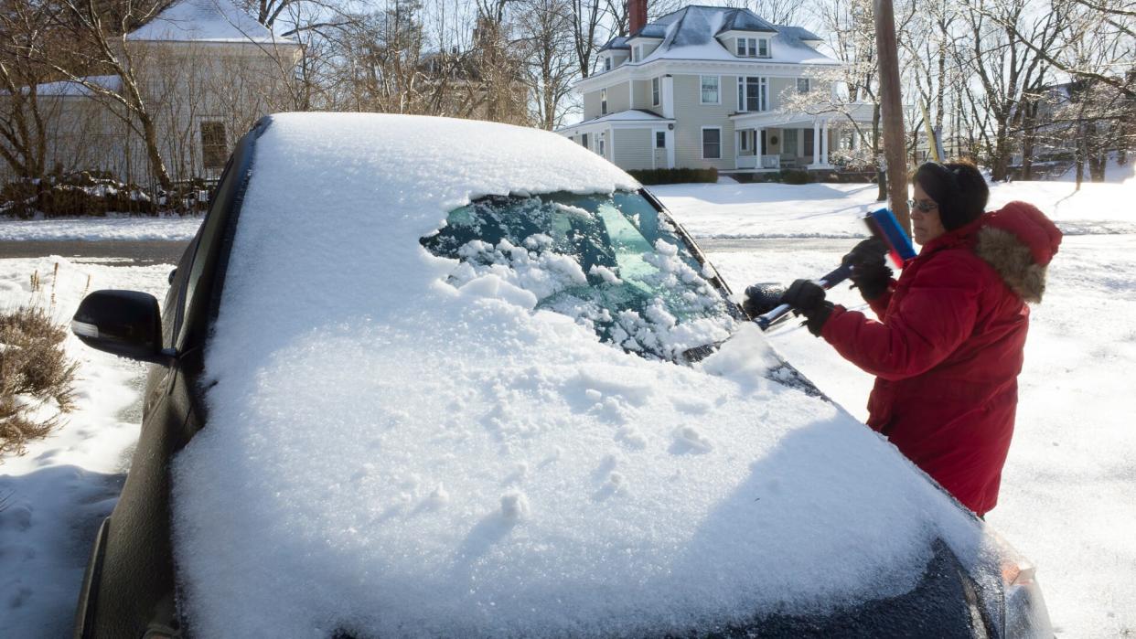 woman scraping snow off her car